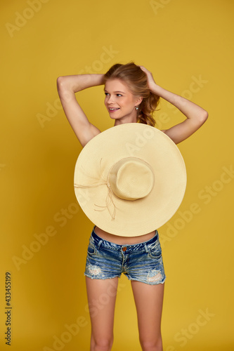 beautiful young blonde woman in shorts with straw hat