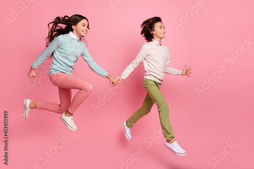 Full length body size view of nice trendy cheerful kids jumping having fun walking isolated over pink pastel color background