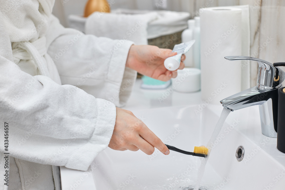 female hand holding toothbrush with paste in bathroom female hand holding toothbrush with paste in bathroom