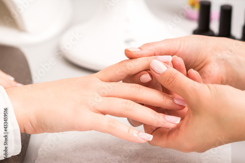 Manicure master massaging client's female fingers after nail polishing in a nail salon