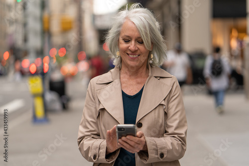 Картината върху платно Mature caucasian woman in city walking street using cellhpone