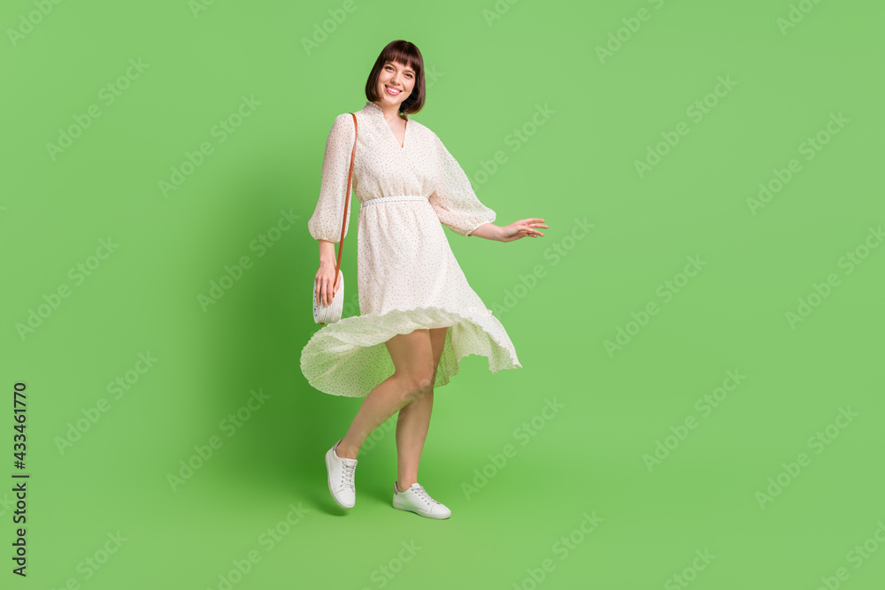 Full length body size side profile photo smiling woman throwing dotted dress skirt in spring isolated pastel green color background Full length body size side profile photo smiling woman throwing dotted dress skirt in spring isolated pastel green color background