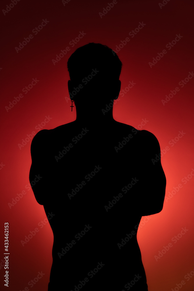 Silhouette of a young man with crossed arms