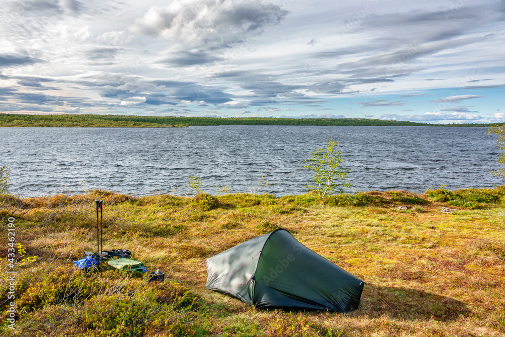 Solo tent at a lakeshore in a wild landscape