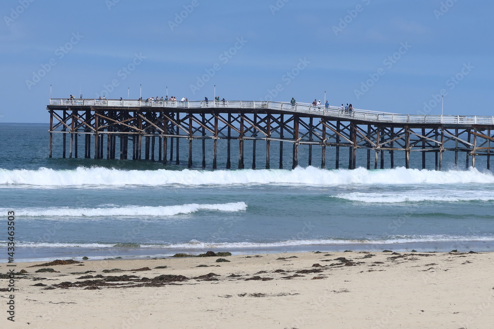 People Enjoying a San Diego, California Beach on a Sunny Day with a  Pier in the Background as Waves Roll Onshore