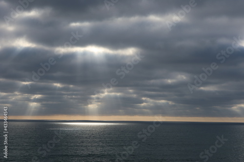 A Cloudy California Sunset with Shafts and Streams of Light Dancing on the Water as a Reflection and Waves Clearly Seen