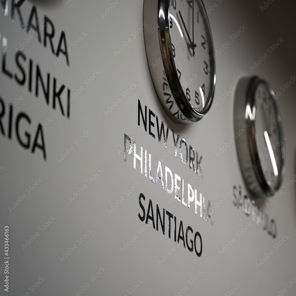 Many wall clocks on the white wall of business office showing time of different cities of the world