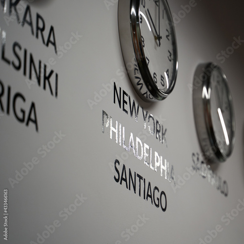 Many wall clocks on the white wall of business office showing time of different cities of the world