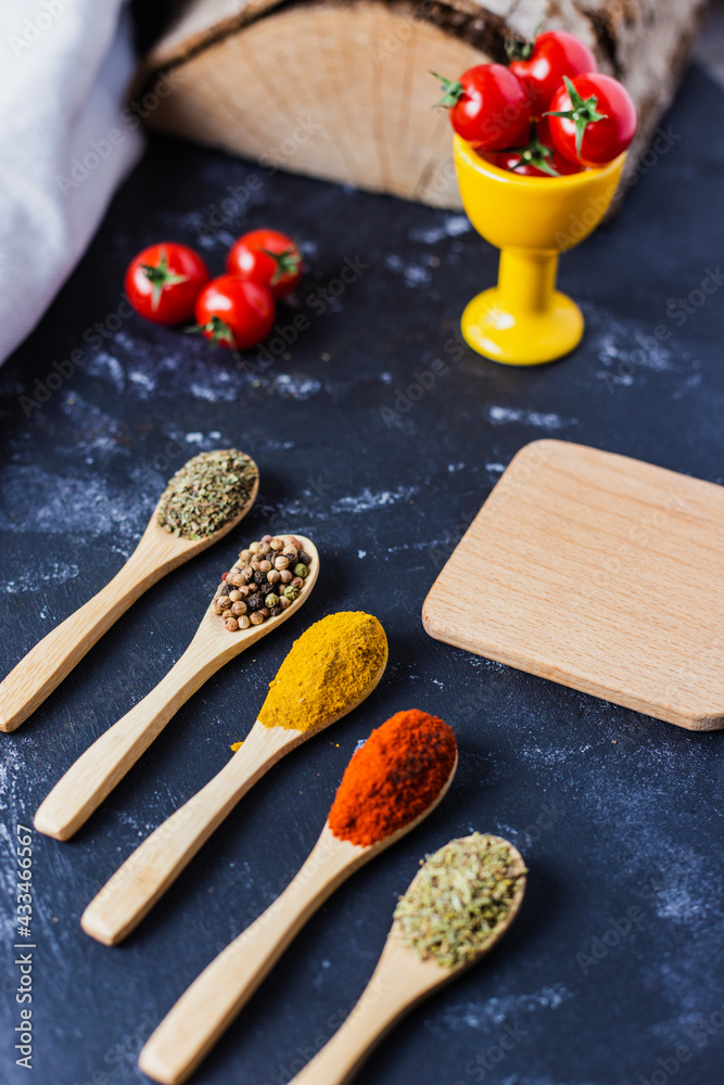 spoons with spices, paprika, basilic, pepper, thyme with cherry tomatoes spoons with spices, paprika, basilic, pepper, thyme with cherry tomatoes