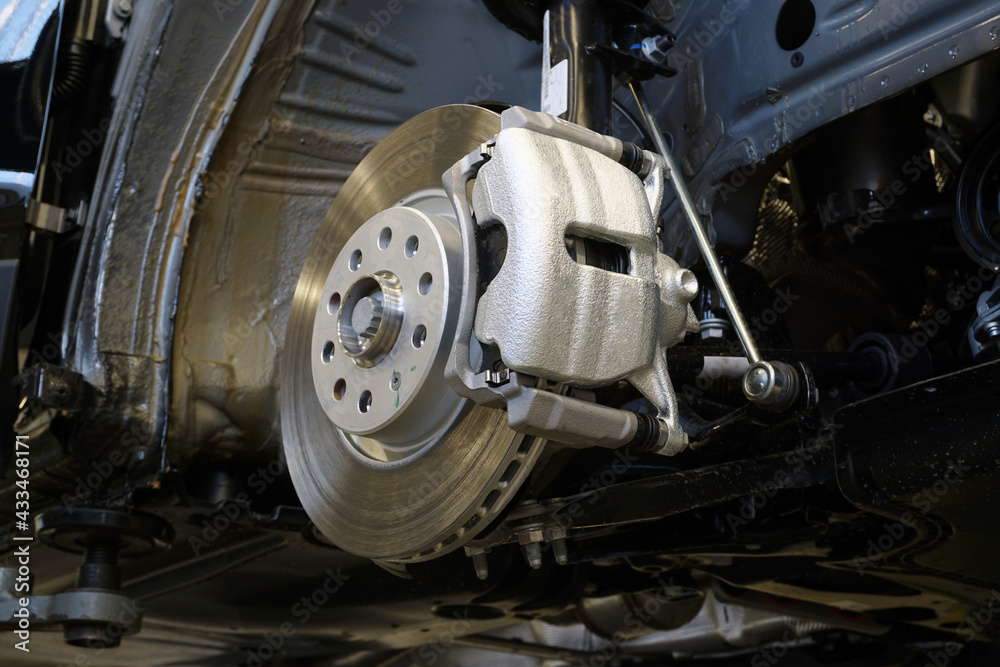 Brake disc and brake caliper installed on a modern car. Car service and spare parts. Brake disc and brake caliper installed on a modern car. Car service and spare parts.