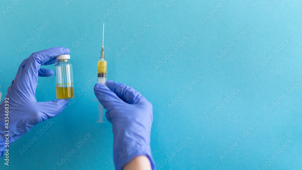 vaccination concept, in hands syringe and glass vial with medicine for injection close-up, blue background with copy space vaccination concept, in hands syringe and glass vial with medicine for injection close-up, blue background with copy space