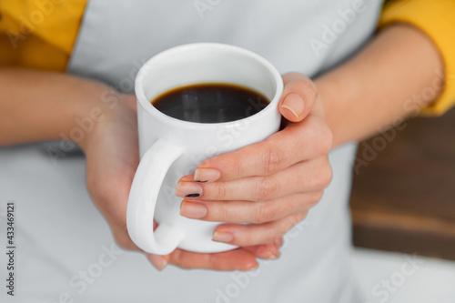 cropped view of woman holding white cup of coffee