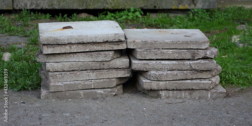 Two piles of gray concrete slabs on the green grass