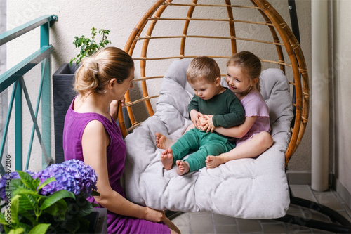 Mother son and daughter are sitting on the balcony and laughing