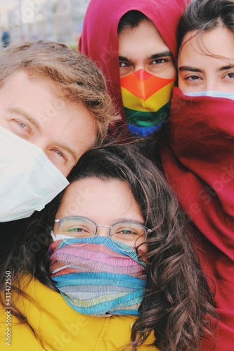 group of friends of different ethnicity and gender identity together with face masks looking at camera outdoors - portrait version photo