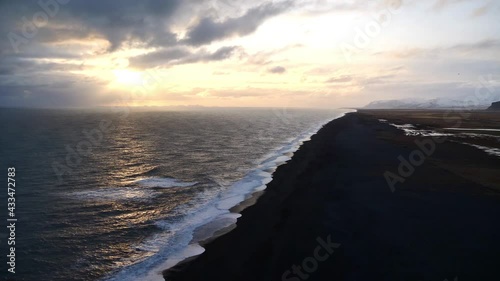 Stunning aerial view over the southern coast of Iceland near Vík í Mýrdal with long black beach Sólheimasandur and Vestmannaeyjar islands on horizon before sunset with sun breaking through clouds. photo