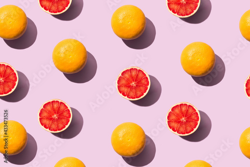 Fototapeta Naklejka Na Ścianę i Meble -  Sunlight Grapefruit pattern made with whole and half pieces on powder pink background. Creative summer food concept. Minimal flat lay with shadow.