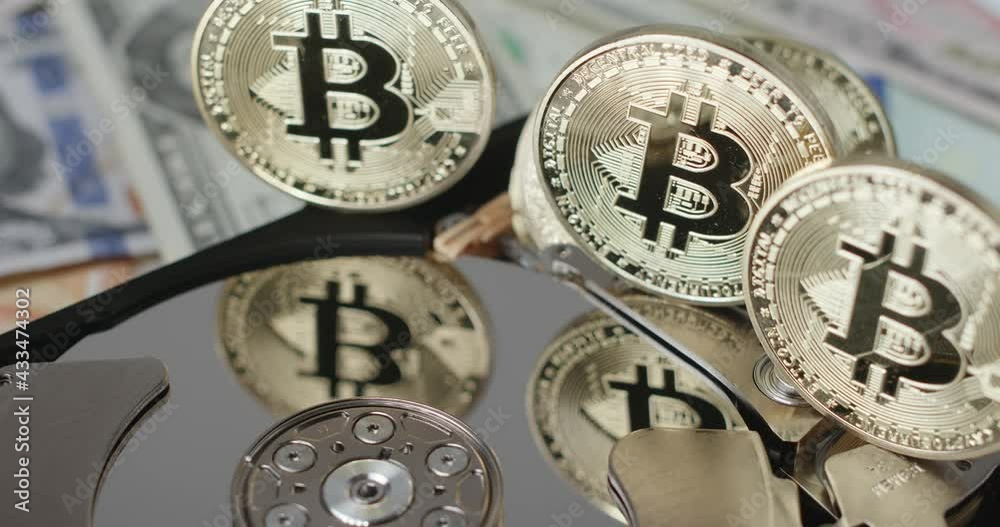 Focus shifting on Gold Bitcoin coins reflecting on HDD disk. Digital money technology concept Focus shifting on Gold Bitcoin coins reflecting on HDD disk. Digital money technology concept