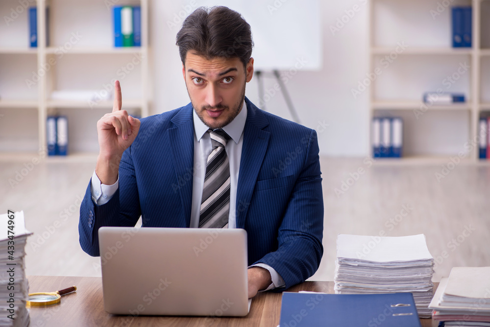 Young male employee unhappy with excessive work in the office Young male employee unhappy with excessive work in the office