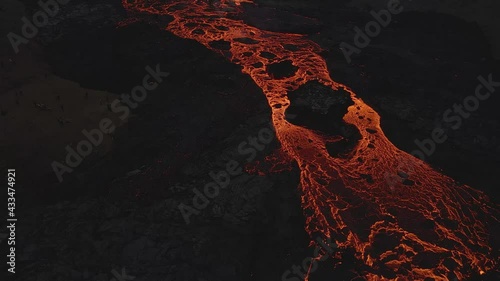 Lava flow spurting from fracture of volcanic crater, Iceland. Aerial forward tilt up reveal  photo
