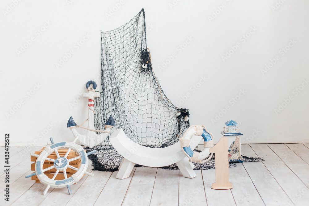 Birthday decor in the style of a sea trip. Suitcases and anchor, lifebuoy, flashlight. Sea thematic photo session decoration in studio.