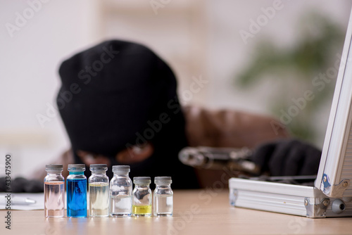 Fotografie Young man in balaclava stealing vaccine from the lab