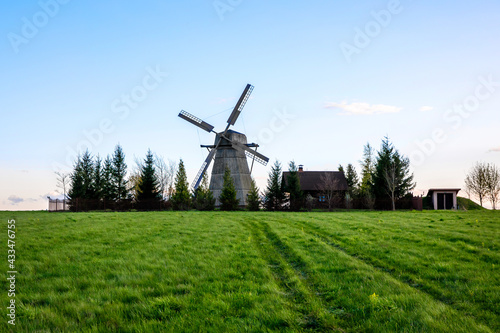 Old wooden windmill in a green field.