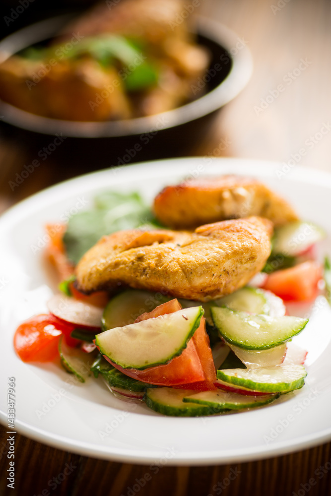fried chicken fillet with fresh cucumbers, tomatoes and radishes in a plate fried chicken fillet with fresh cucumbers, tomatoes and radishes in a plate