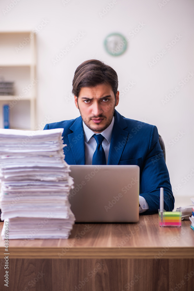 Young businessman employee unhappy with excessive work in the office Young businessman employee unhappy with excessive work in the office