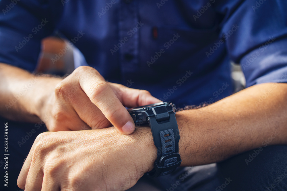 businessman wearing digital smart watch in hand  touching screen to open notification, read message and activity tracker in wrist with soft-focus and over light in the background.