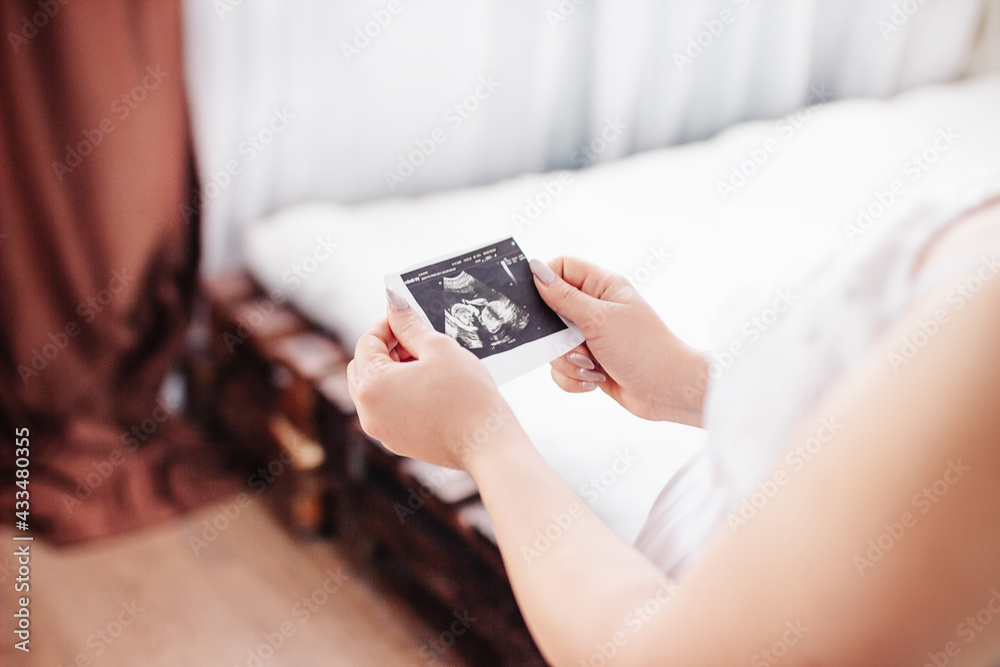 Pregnant woman looks at ultrasound photo Pregnant woman looks at ultrasound photo