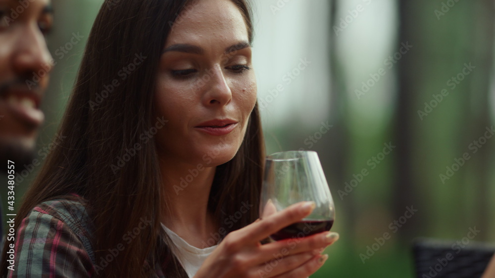 Beautiful girl resting with friends outside. Woman drinking wine on party