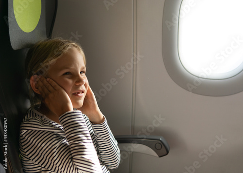 A girl holds her ears on a plane. My ears hurt on the plane.