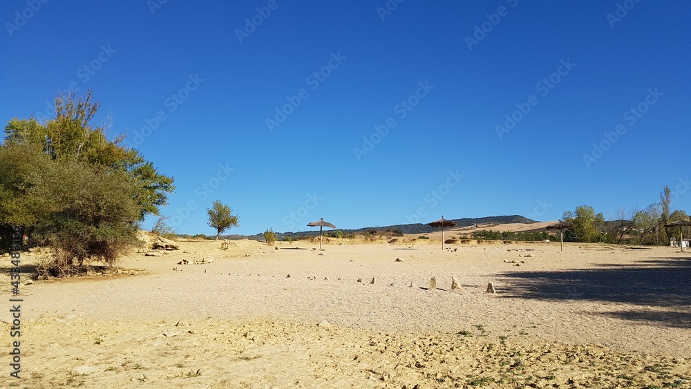 la playa de un lago de montañas en España con sombrillas de bambú la playa de un lago de montañas en España con sombrillas de bambú