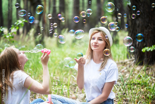 Two young women blowing bubbles in park