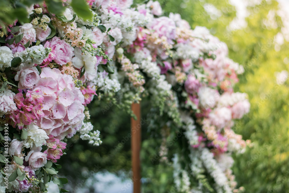 Obraz premium Close up of very beautiful and stylish wedding arch, decorated with various fresh flowers, standing in the garden.