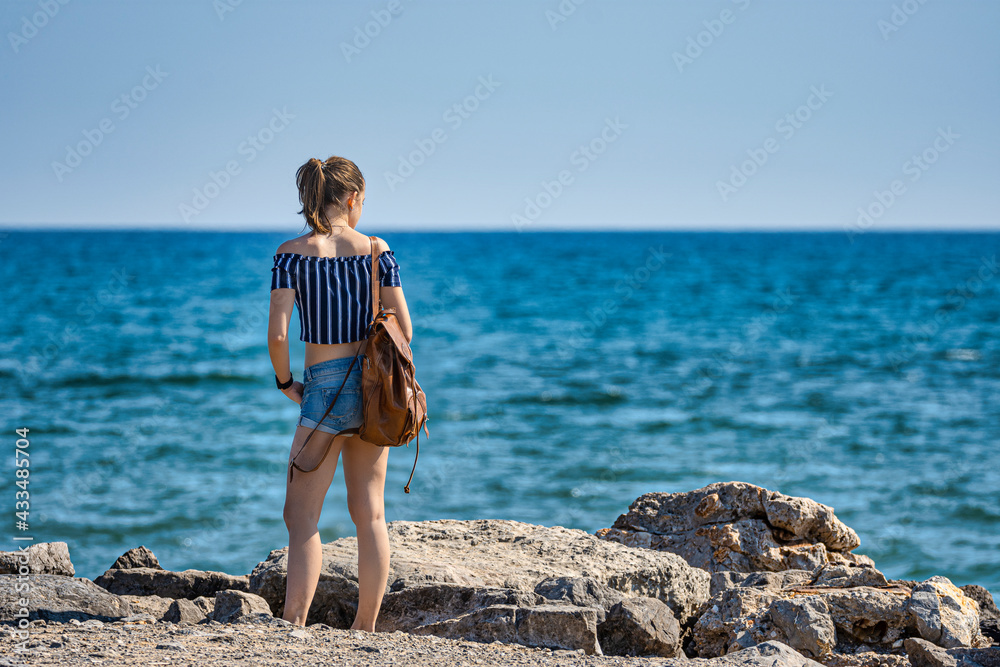 young girl with her back turned on the edge of the sea