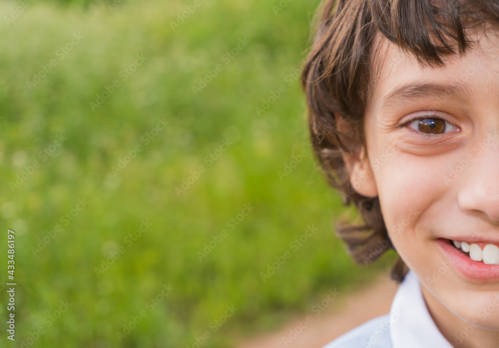 half face of a white boy with a white shirt brown hair and a little long, smiling and green vegetation background and a path. half face of a white boy with a white shirt brown hair and a little long, smiling and green vegetation background and a path.