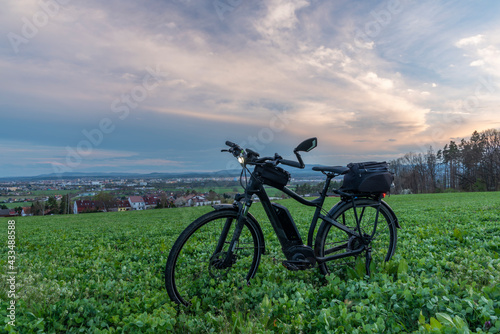 Fototapeta Naklejka Na Ścianę i Meble -  Black and gray electric bicycle in sunset time with cloudy sky