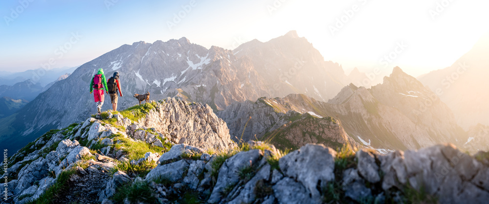 two hikers with dog in the mountains - obrazy, fototapety, plakaty 