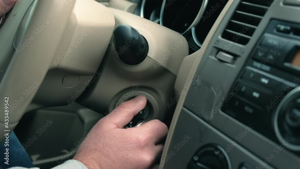 Man's hand puts the car key in the keyhole, starting the car. Man's hand puts the car key in the keyhole, starting the car.
