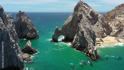 Aerial view of the Arch of Cabo San Lucas with some waves crashing in the rock, the drone slowly rotating.