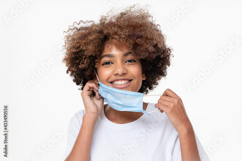 Vászonkép Smiling african american school girl taking off face mask after the end of pandemic