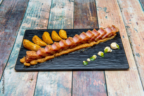 Spanish torrezno with techno-emotional cooking style on a bed of mashed potatoes and chips photo