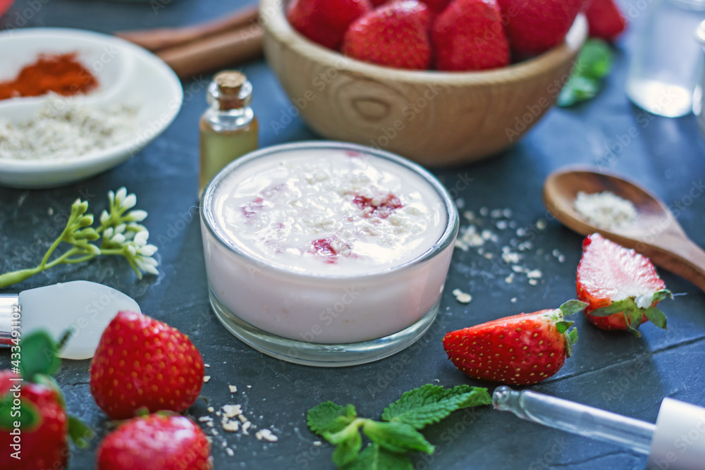 Homemade strawberry face mask with oatmeal and cream on a dark background. Concept of natural handmade cosmetics Homemade strawberry face mask with oatmeal and cream on a dark background. Concept of natural handmade cosmetics