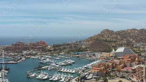 Aerial panoramic view of the Marina in Cabo San Lucas, the drone flying in El Medano Beach with a blue sky as background.
