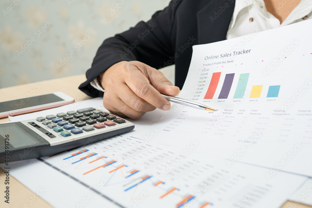 Asian accountant working and analyzing financial reports project accounting with chart graph and calculator in modern office, finance and business concept. Asian accountant working and analyzing financial reports project accounting with chart graph and calculator in modern office, finance and business concept.