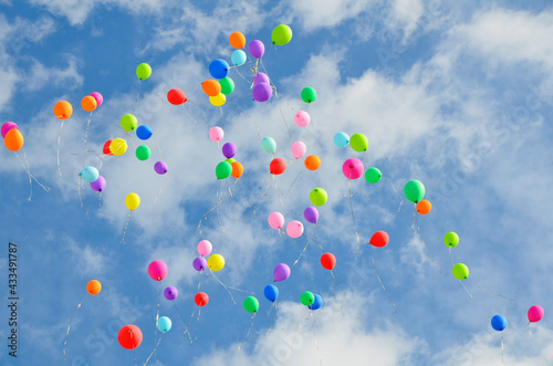 Lots of colorful balloons flying against blue sky with clouds with copy space. Concept of holiday, festival, Children's Day, Last call at school and kindergarten, birthday.