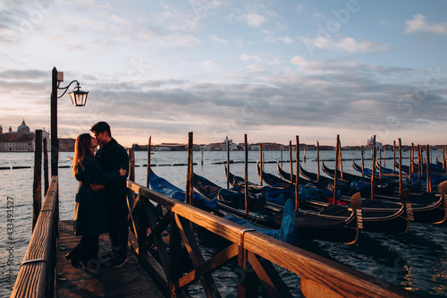 A romantic evening walk by a young Asian couple at the pier. A young couple travels to Venice. © dimadasha