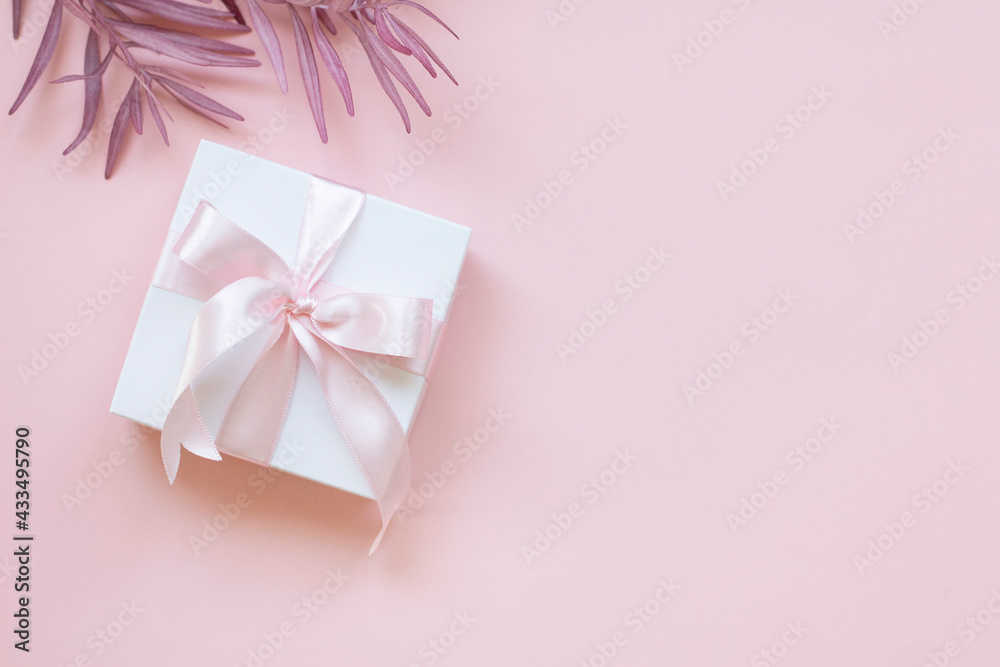 A gift box and pink flowers on a pink background. Gift box background. A gift box and pink flowers on a pink background. Gift box background.